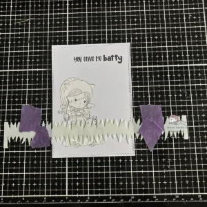 Grass stencil placed over the background while masking paper protects the stamped image — ink blending step in how to make a Halloween card step-by-step.