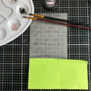 Brick wall background card with post-its masking the bottom, showing palette with black acrylic paint and brushes used for paint splatters