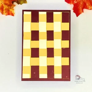 Paper woven autumn background Handmade woven paper card background made of thin paper strips in cream, mustard, and burgundy, creating a cozy autumn weave
