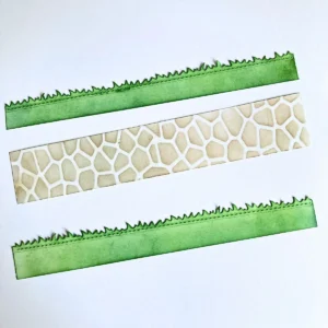 Die cut green grass strips and a stone patterned path strip prepared for an interactive slimline card.
