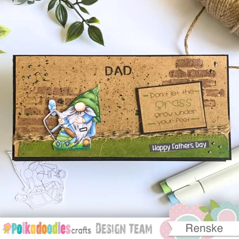The finished slimline card sits on white surface with alcohol markers and twine nearby. The design features a Lawn Mower Gnome on a green grass border with a DAD sentiment. This gardening Father’s Day card combines rustic textures and an earthy colour palette beautifully