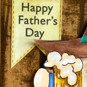 Happy Father's day sentiment close up A close up of a handmade banner with the words Happy Father’s Day printed on a warm background. The inked edges help the greeting blend naturally into the rustic woodgrain background of the card.