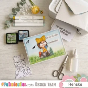 A finished handmade school card displayed on a wooden crafting table. The project sits alongside Distress Ink pads and alcohol markers that were used to build the scene.