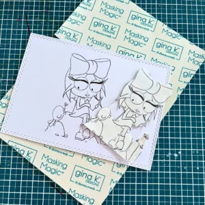 A paper mask cut from masking paper is placed over a printed digital stamp outline on white cardstock. Perfect for the masking technique. This step protects your main image during the background ink blending process.